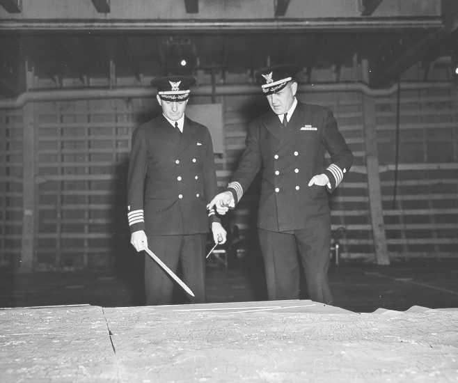 UNSUNG HEROES: Coast Guard Captains Edward Fritzche (left) and Miles Imlay (right) discuss the invasion of Omaha Beach on a relief map laid out in the hold of the Samuel Chase. UNSUNG HEROES: Coast Guard Captains Edward Fritzche (left) and Miles Imlay (right) discuss the invasion of Omaha Beach on a relief map laid out in the hold of the Samuel Chase.
